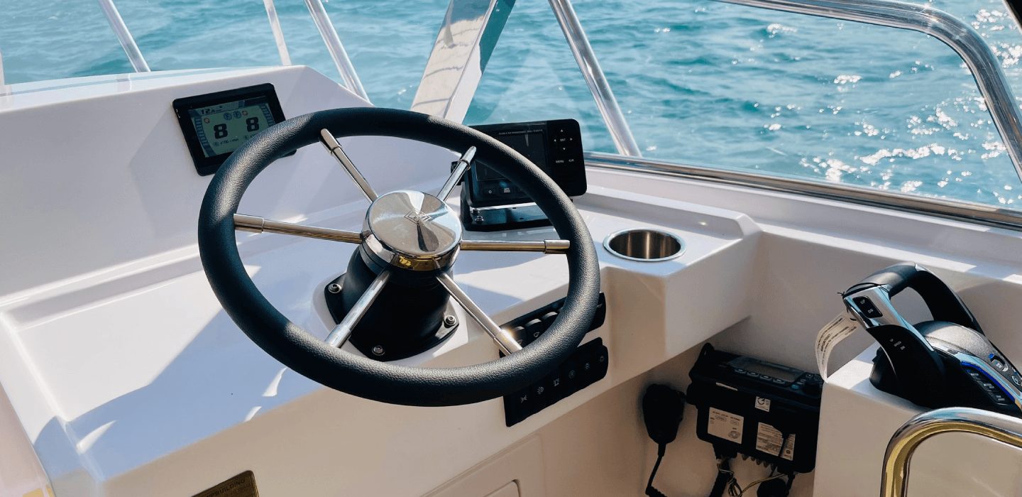 Buồng lái hiện đại của tàu khách C10 với vô lăng và màn hình điều khiển. Modern cockpit of passenger boat C10 with steering wheel and control screens.