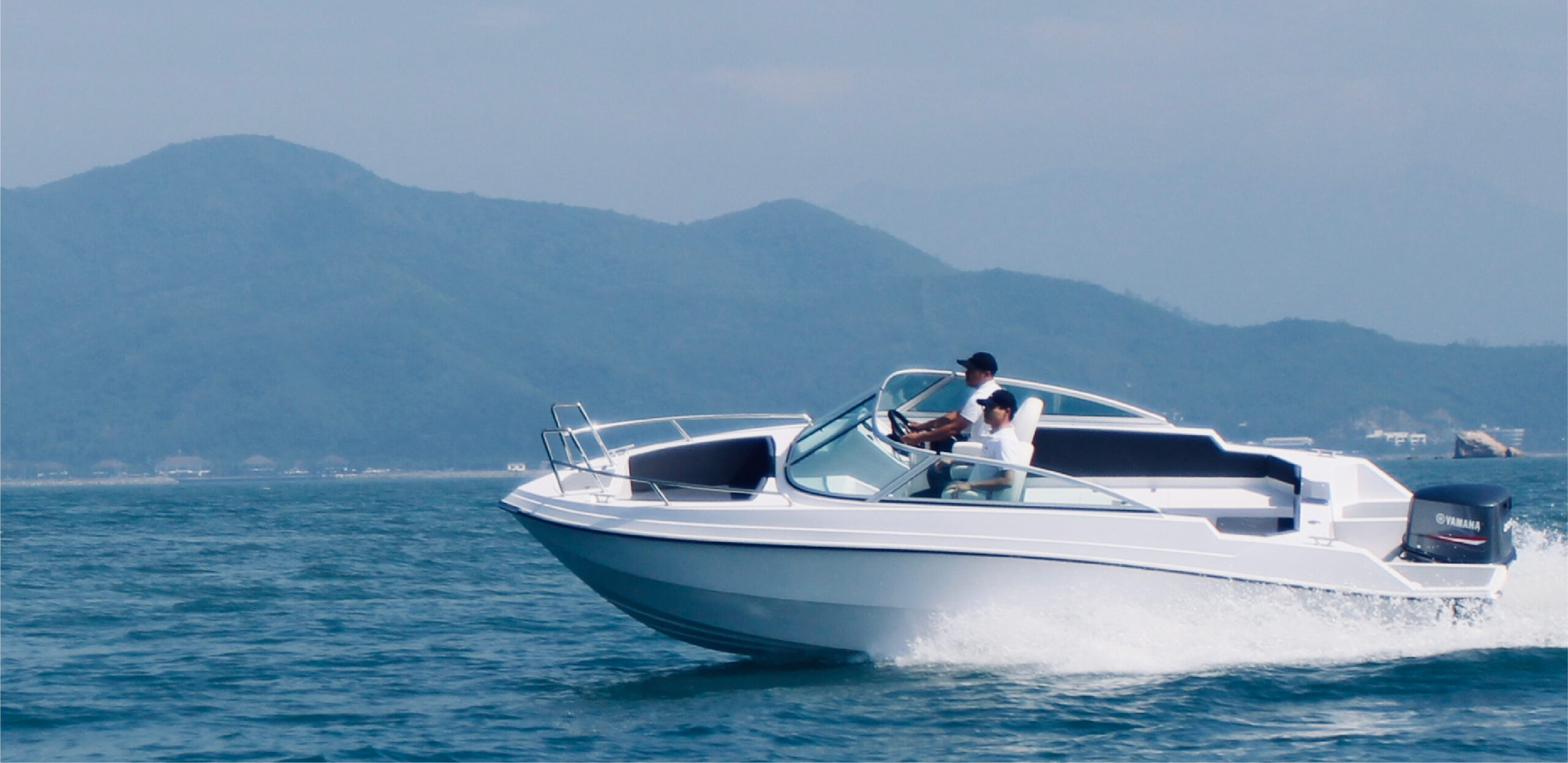Ca nô Sông Lô C6 di chuyển trên vịnh với khung cảnh núi non – Song Lo C6 powerboat gliding across the bay with mountain backdrop
