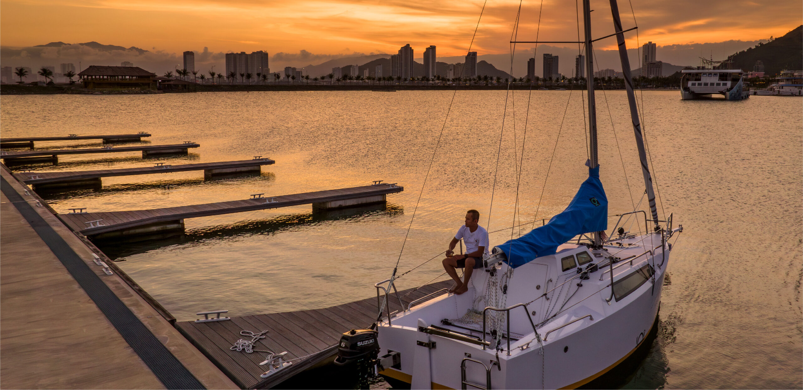 Người trải nghiệm trên thuyền buồm Seanata 580 khi hoàng hôn tại bến cảng – Sailing Seanata 580 at sunset in the marina